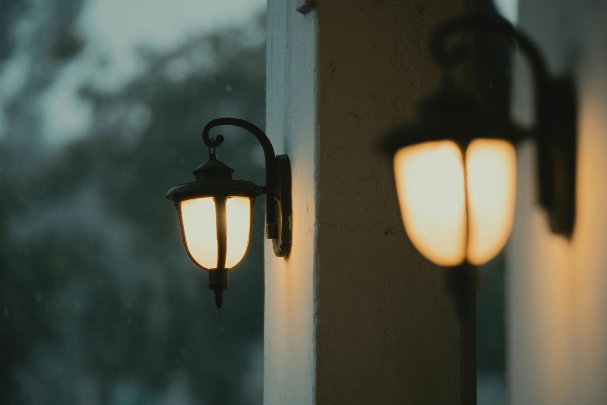 Kültéri falilámpák meleg fénnyel egy ház bejáratánál, téli időben.