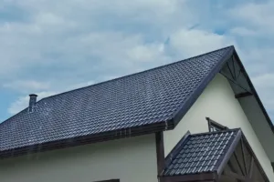 Cserépfedésű nyeregtető egy családi házon, esős időben.